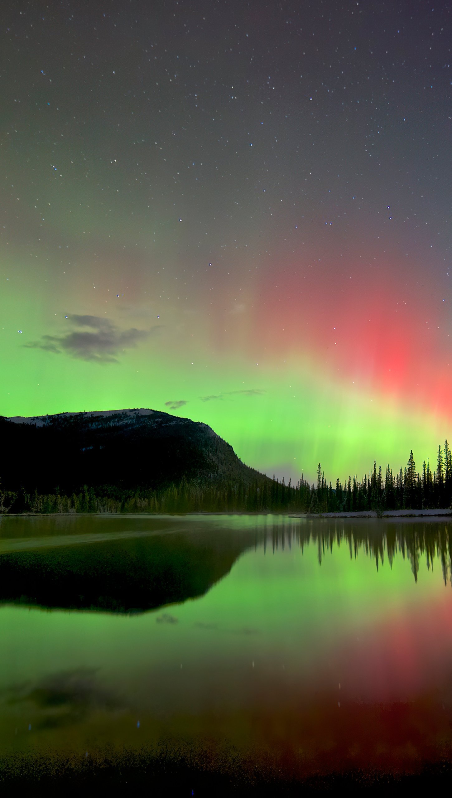 Aurora polar detras de montañas y lago