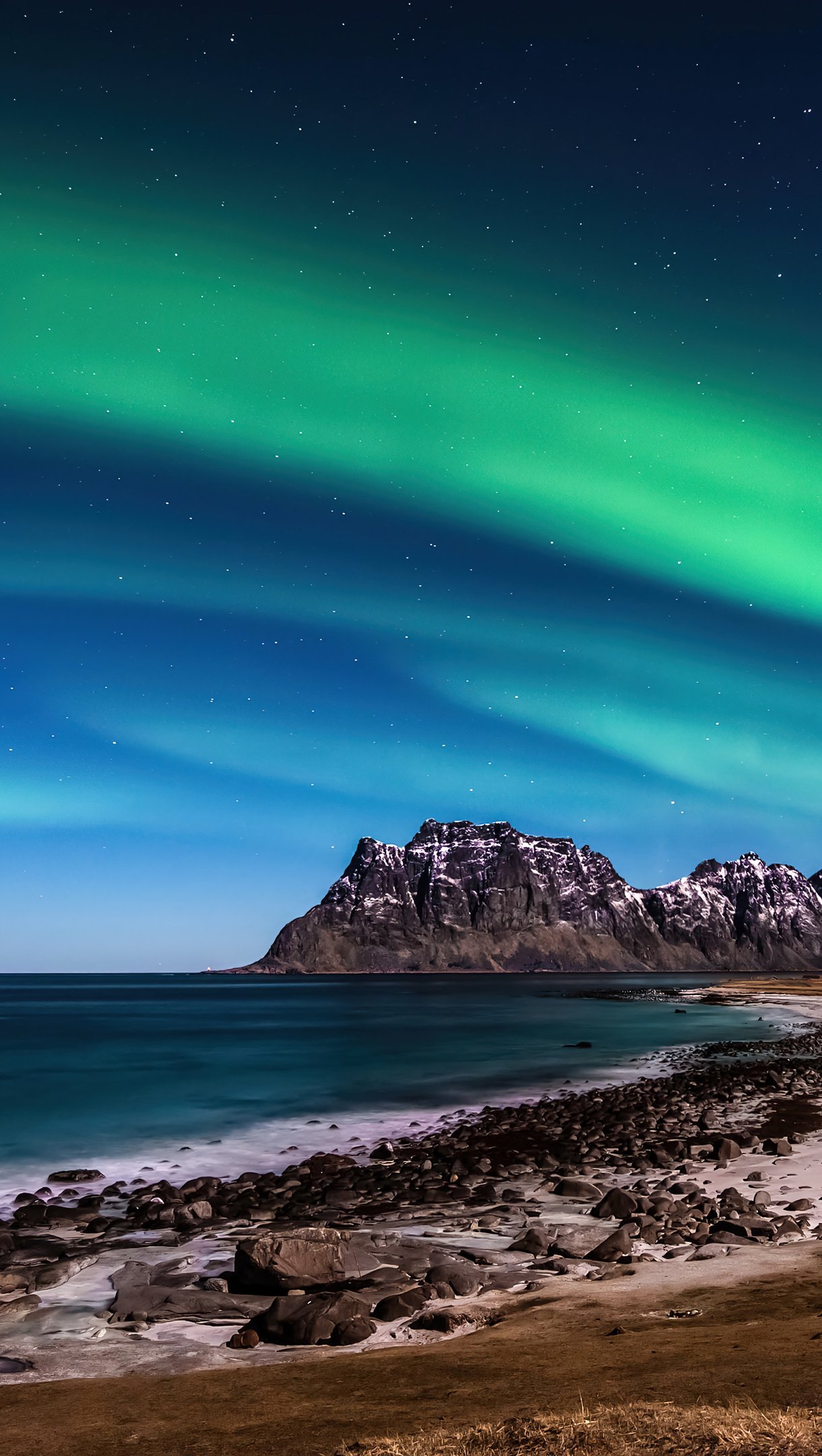 Aurora polar en las montañas frente al mar