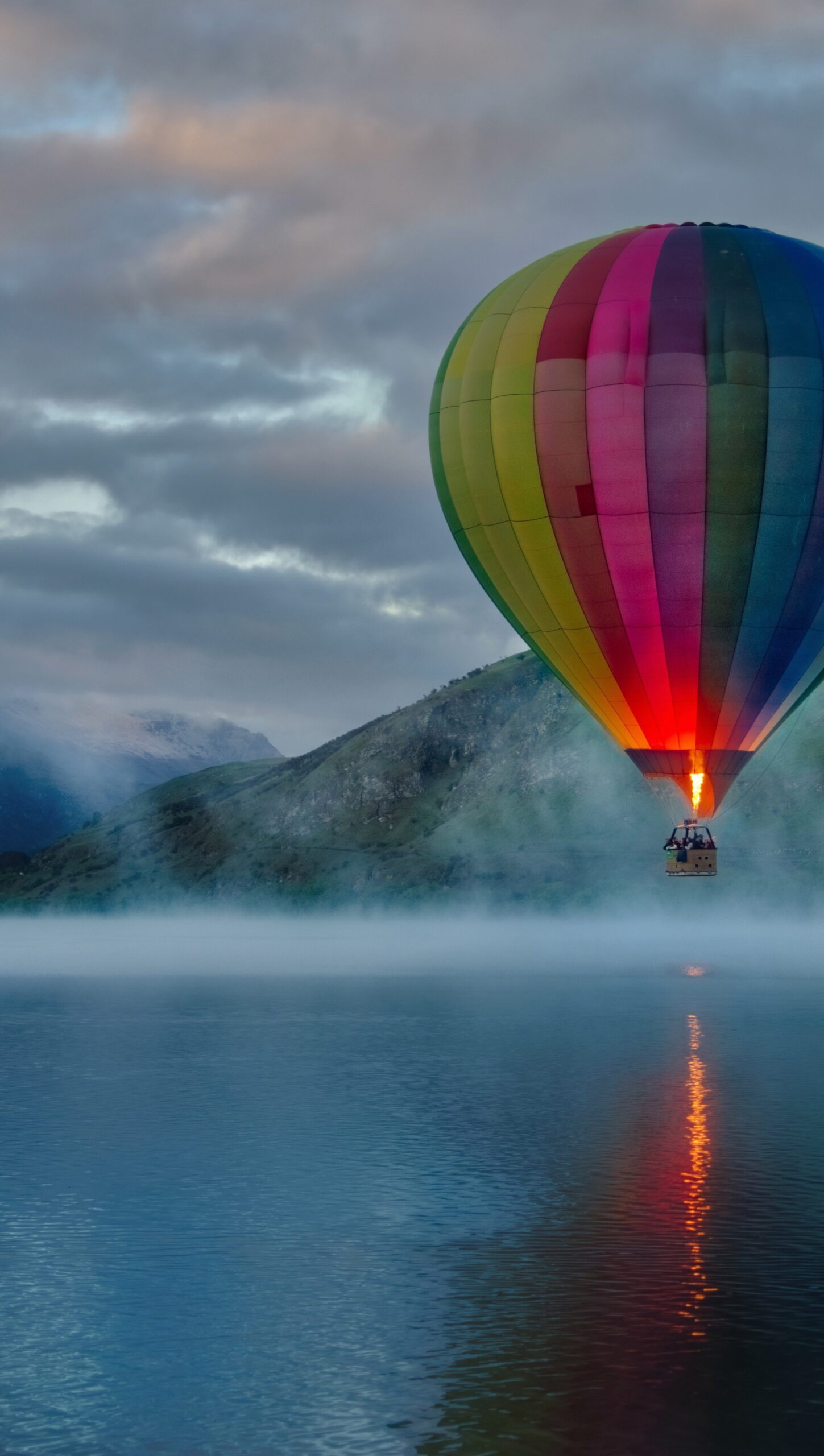 Globo aerostático en lago con montañas