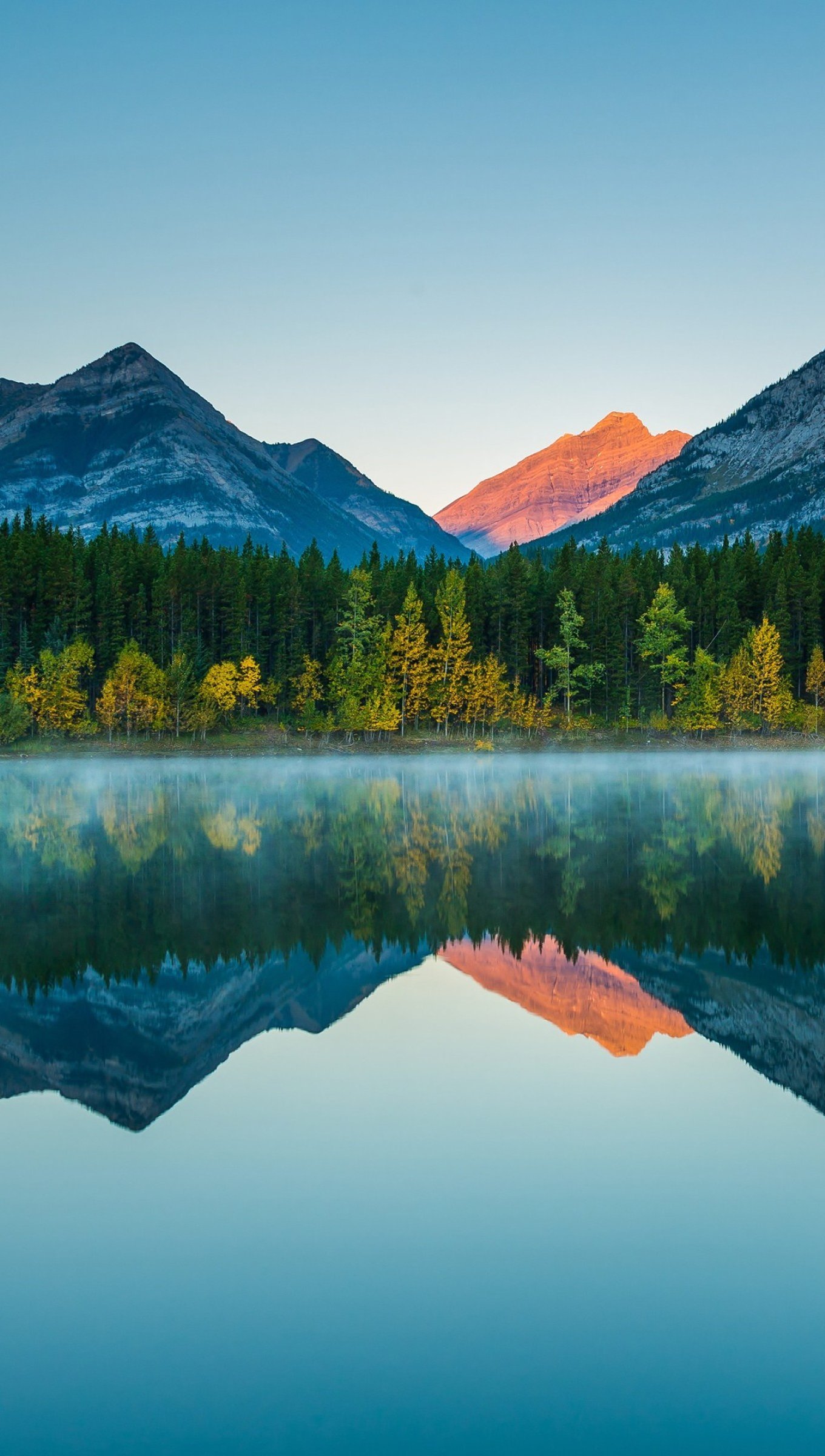 Montañas reflejadas en lago al atardecer